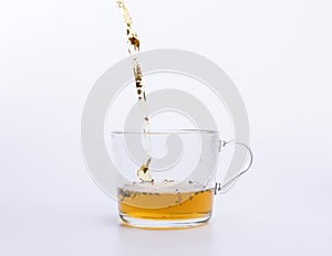 Tea pouring into glass cup isolated on white