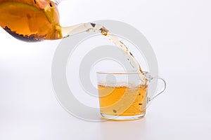 Tea pouring into glass cup isolated on white