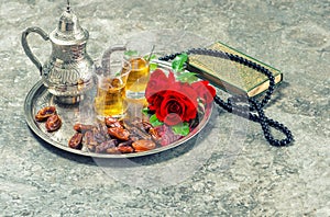 Tea, red rose flower, dates, holy book quran and rosary. Islamic