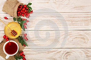 Tea with rose hips and honey on white wooden background with copy space for your text. Top view