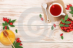 Tea with rose hips and honey on white wooden background with copy space for your text. Top view
