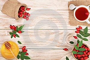 Tea with rose hips and honey on white wooden background with copy space for your text. Top view