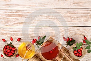 Tea with rose hips and honey on white wooden background with copy space for your text. Top view