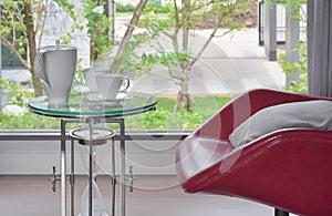 Tea set on glass top table with red easy chair in living room