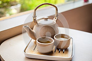 Tea set with kettle and traditional Japanese mugs on a wooden table