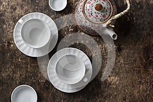 Tea set on a wooden table, top view. Teapot, empty white tea cup on a brown background, top view.