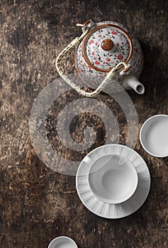 Tea set on a wooden table, top view. Teapot, empty white tea cup on a brown background, top view. Free space