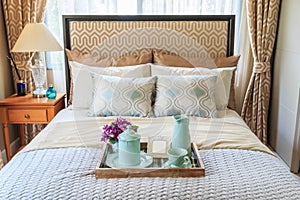 Tea set in a wooden tray on the couch in the bedroom with warm l