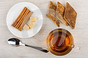 Tea, shortbread with cinnamon, sugar and cinnamon sticks in saucer