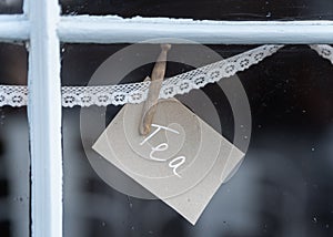 Tea sign pegged to lace in shop window advertising hot drinks