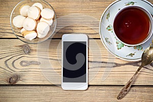 Tea with snack and mobile phone on wooden table