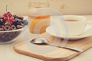 Tea, spoon, honey and flakes with berries/tea, spoon, honey and flakes with berries on a wooden tray. Selective fokus