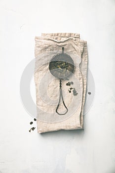 Tea strainer with dry tea on grey background