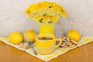 Tea with sugar and lemon, bagels and bouquet of flowers