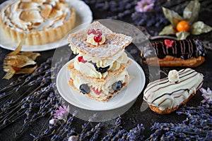 Tea and sweets on a dark background, Mille-feuille, Eclairs, Tart, Decorative with flowers, Selective focus, Closeup