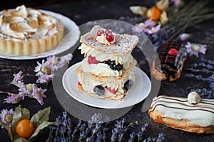 Tea and sweets on a dark background, Mille-feuille, Eclairs, Tart, Decorative with flowers, Selective focus, Closeup