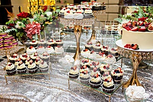 Tea table, a lot of beautiful, bright and delicious cupcakes-cupcakes with cream, strawberries