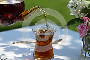 Tea from teapot pours into armudu glass