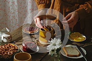 Tea time. Morning breakfast. Woman adds lemon slice into cup of tea.