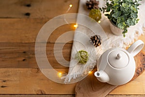 Tea time and tea drinking. White porcelain teapot on a wooden board on a wooden table with a pink garland. View from above. Copy