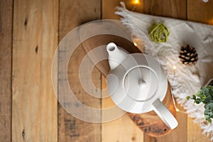 Tea time and tea drinking. White porcelain teapot on a wooden board on a wooden table with a pink garland. View from above. Copy