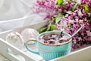 The tea to a karkada served in a gift box with marshmallows and a bouquet of a lilac. Close up.