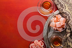 Tea in traditional glass cups  and  turkish delight  on red painted wooden background  with empty space for text . Flat lay. Selec