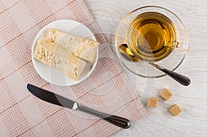 Tea, wafer cake in saucer, knife, sugar, pink napkin