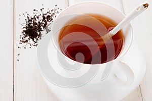 Tea in a white mug with a spoon and tea leaves