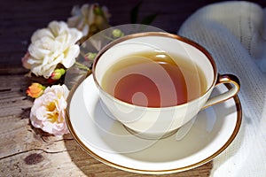 Tea in a white porcelain cup with a gold rim and rose decoration