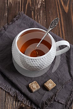 Tea in a white teacup, linen napkin,vintage spoon,wooden dark table.