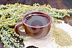 Tea with wormwood in brown cup on board
