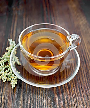 Tea with wormwood in glass cup on board