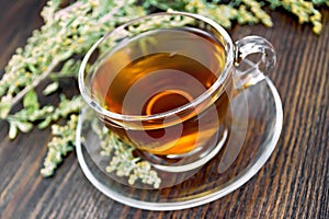 Tea with wormwood in glass cup on dark board