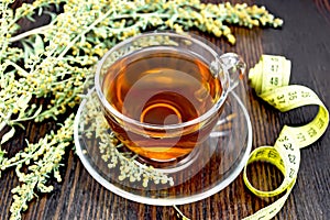 Tea with wormwood in glass cup and meter on board