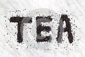 Tea written with black Earl Gray leaves