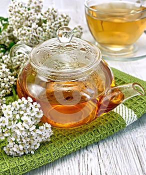 Tea with yarrow in glass teapot on board