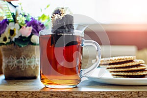 Teabag dipped into hot water. Black tea swirls in fresh liquid. Sachet brewing in hot beverage flow. Antioxidant healhty drink