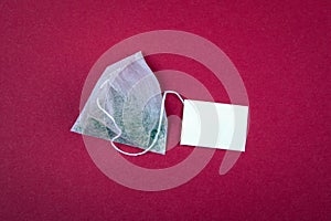 Teabag with white label. Top view, on a red background. Mockup