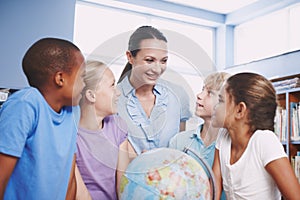 Teach us more about the world. A pretty young geography teacher teaching her students about the world using a globe of