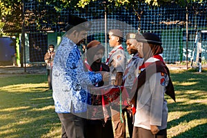 A teacher as the supervisor of the ceremony hangs the sign of the scouting participants at the school.