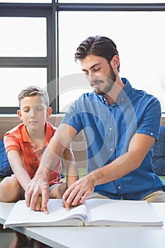 Teacher assisting blind student in library