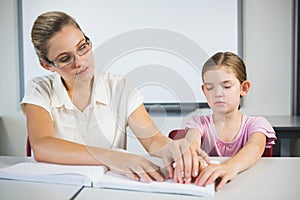 Teacher assisting blind student in library