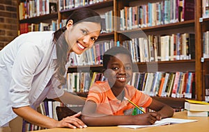 Teacher assisting boy with homework in library