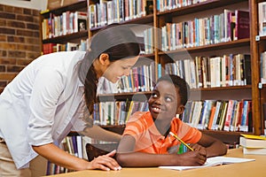 Teacher assisting boy with homework in library