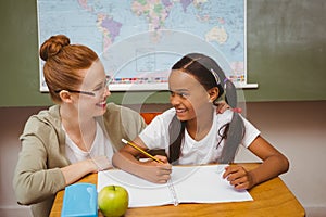 Teacher assisting girl with homework in classroom