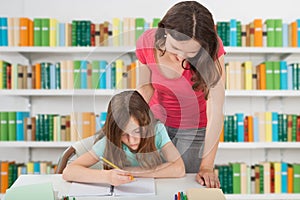 Teacher Assisting Girl At School Library