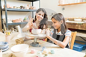 Teacher Assisting Girl To Unleash Her Creativity Of Pottery Pain