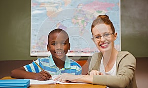 Teacher assisting little boy with homework in classroom