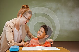 Teacher assisting little boy with homework in classroom